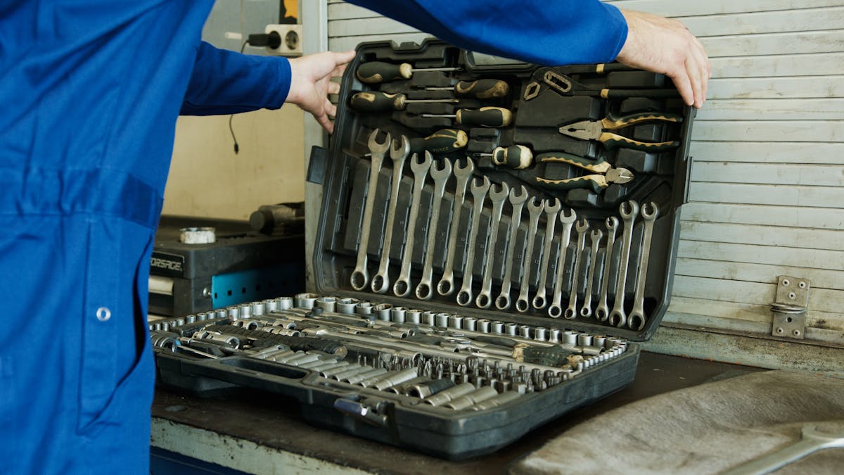 Plumber in a blue uniform holding an open toolbox full of tools