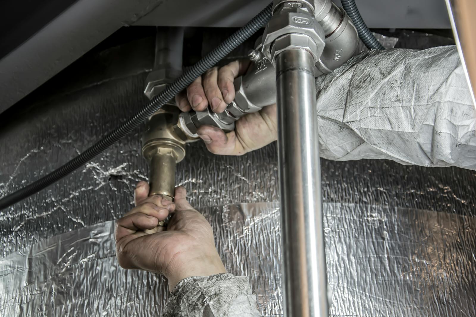 Plumber tightening a copper pipe fitting with a wrench